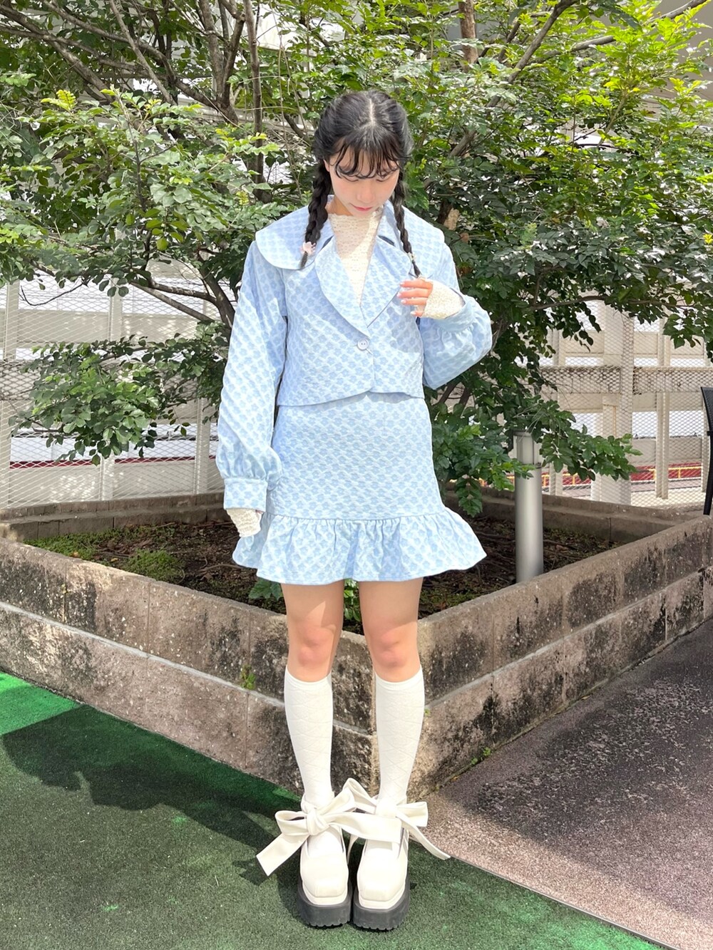 ブルー系のスカート、ホワイト系のパンプス、ブルー系のテーラードジャケットを着用したレディースの春コーディネートの2枚目の写真