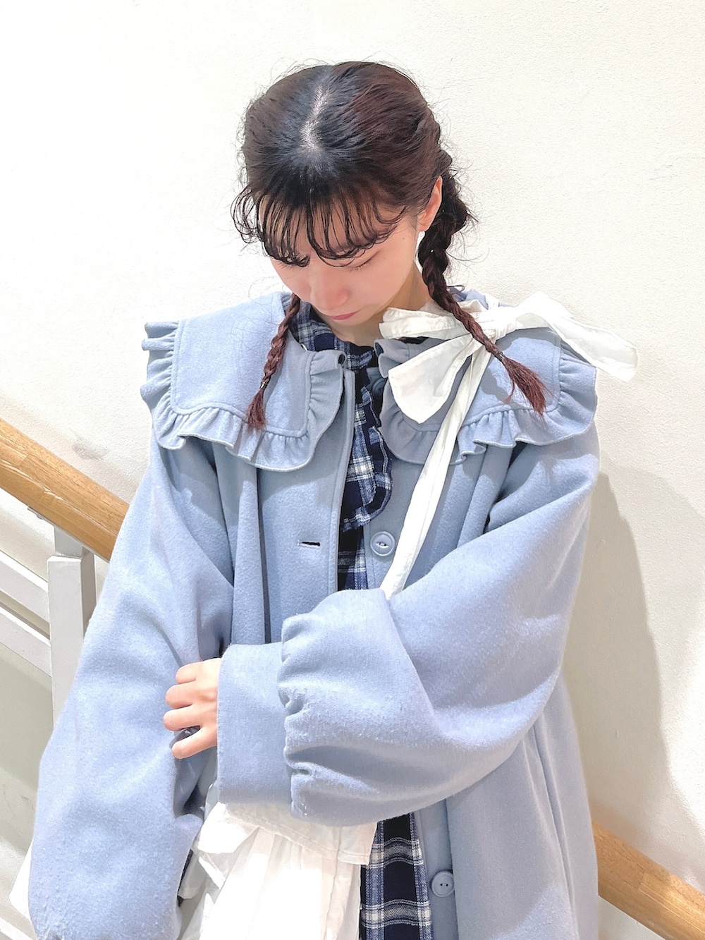 ブルー系のチェスターコート、ブルー系のワンピース、ホワイト系のショルダーバッグを着用したレディースの冬コーディネートの4枚目の写真