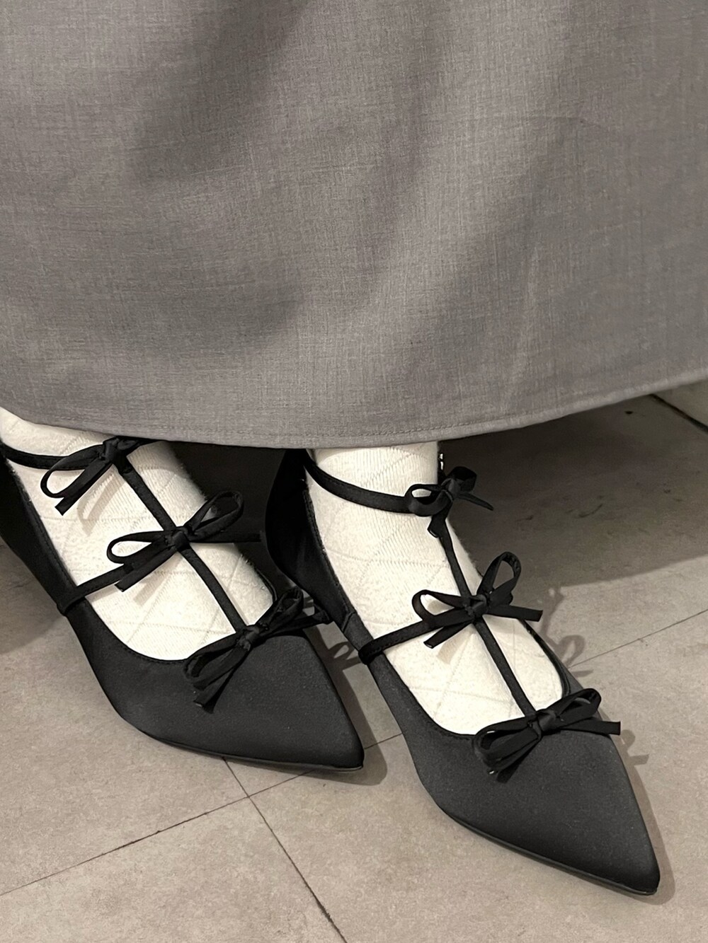 ブルー系のニット/セーター、グレー系のスカート、ブラック系のパンプスを着用したレディースの春コーディネートの6枚目の写真