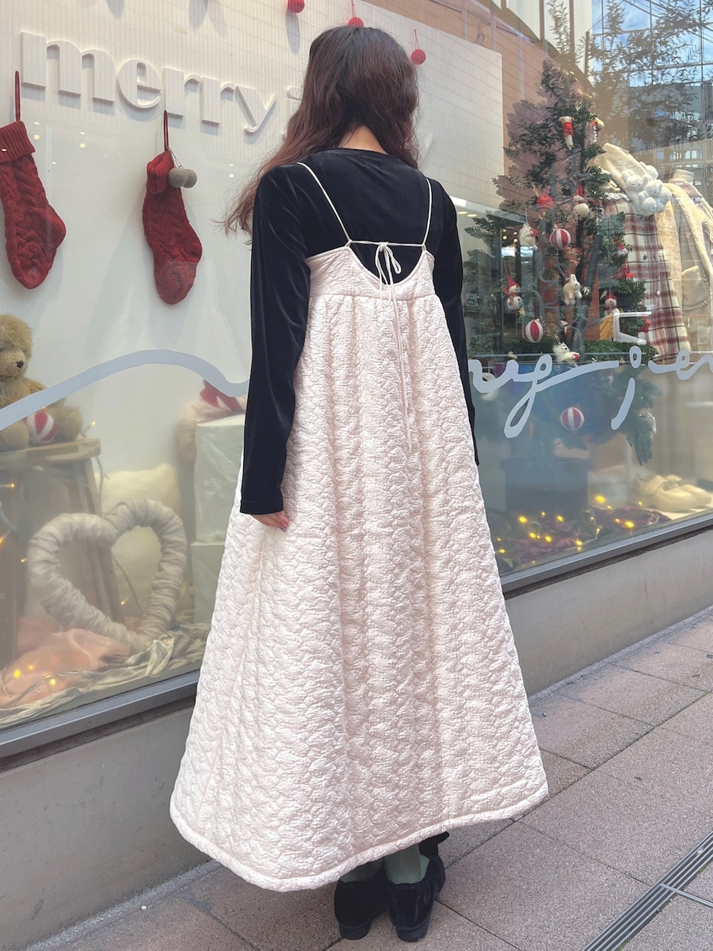 ピンク系のチェスターコート、ブラック系のカーディガン/ボレロ、ホワイト系のワンピースを着用したレディースの冬コーディネートの6枚目の写真