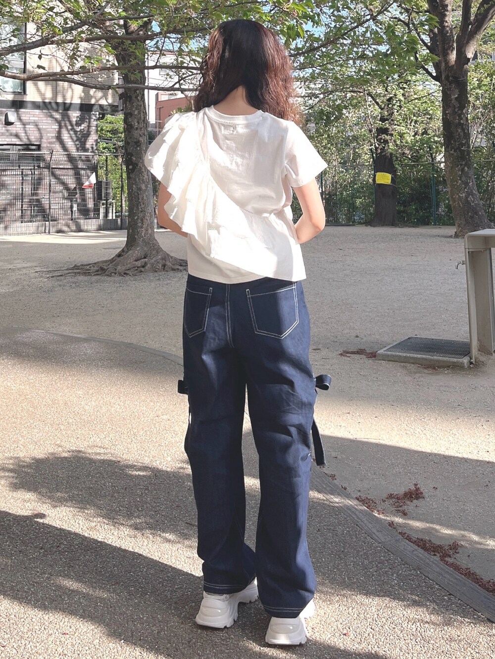 ホワイト系のTシャツ/カットソー、ブルー系のデニムパンツ、ホワイト系のスニーカーを着用したレディースの春コーディネートの2枚目の写真