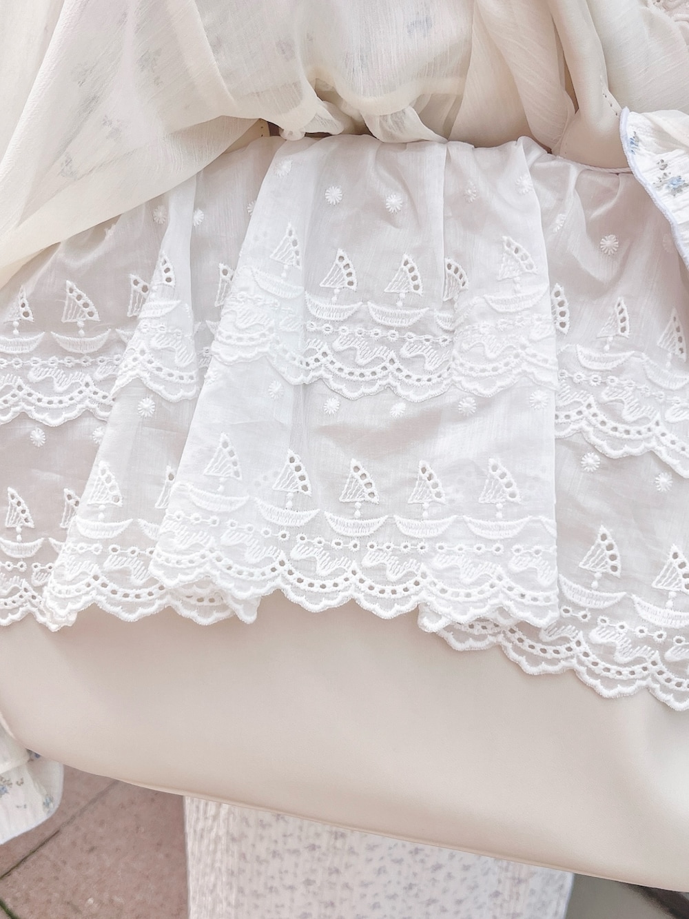 ホワイト系のカーディガン/ボレロ、ブルー系のTシャツ/カットソー、パープル系のスカートを着用したレディースの春コーディネートの9枚目の写真