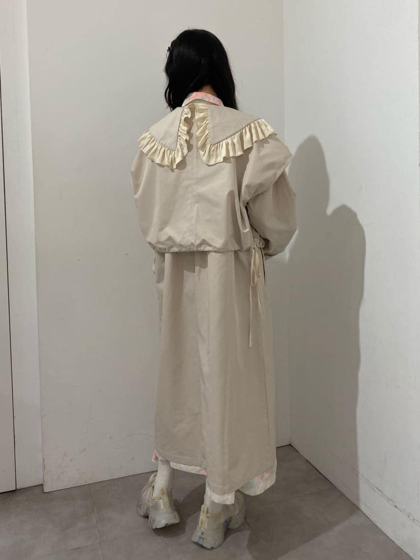 ホワイト系のトレンチコート、ピンク系のワンピース、ホワイト系のスニーカーを着用したレディースの冬コーディネートの3枚目の写真