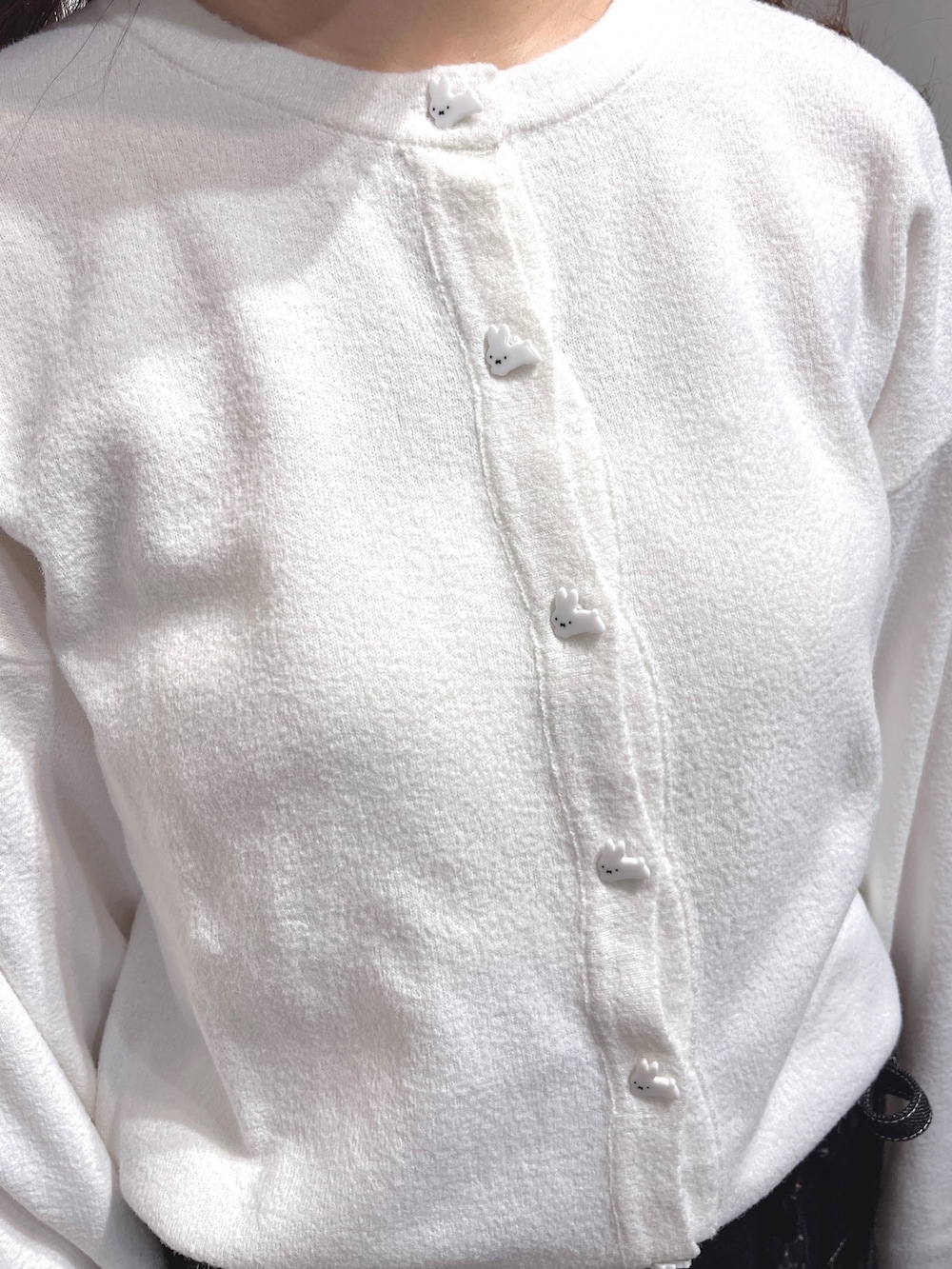 ホワイト系のカーディガン/ボレロ、ブラック系のデニムスカート、ブラック系のスニーカーを着用したレディースの冬コーディネートの8枚目の写真