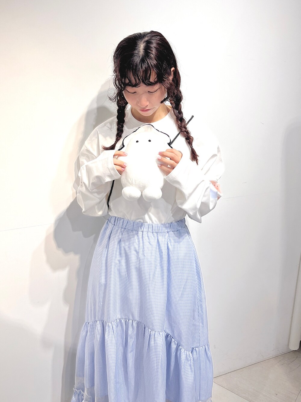 ホワイト系のショルダーバッグ、ホワイト系のTシャツ/カットソー、ブルー系のスカートを着用したレディースの冬コーディネートの5枚目の写真