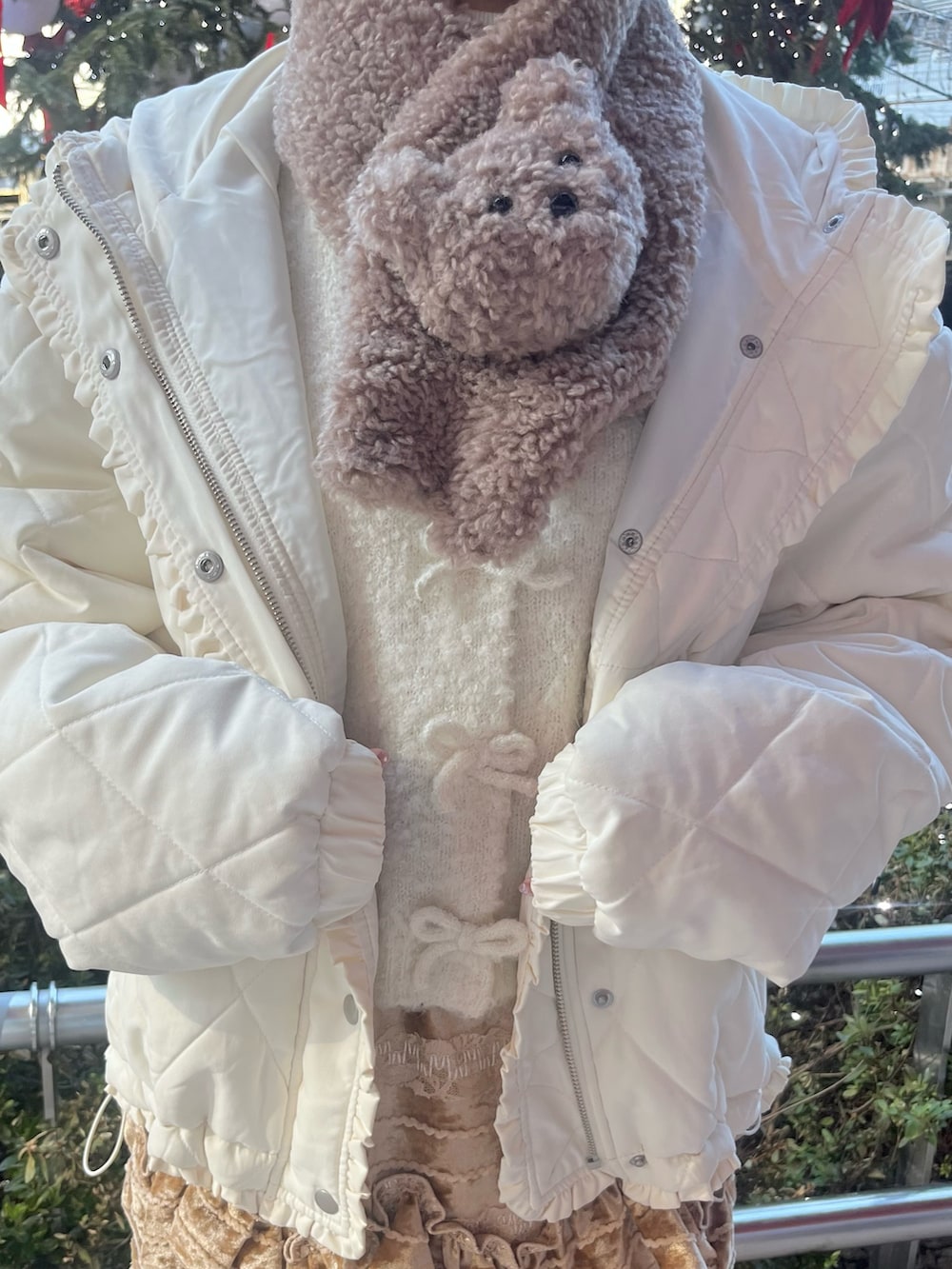 ホワイト系のカーディガン/ボレロ、ホワイト系のダウンジャケット/コート、ブラウン系のスカートを着用したレディースの冬コーディネートの5枚目の写真