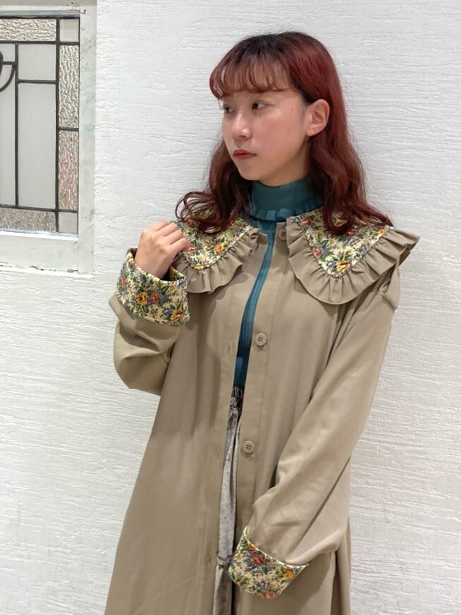 ブラウン系のスカート、ベージュ系のトレンチコート、ブラウン系のブーツを着用したレディースの秋コーディネートの3枚目の写真