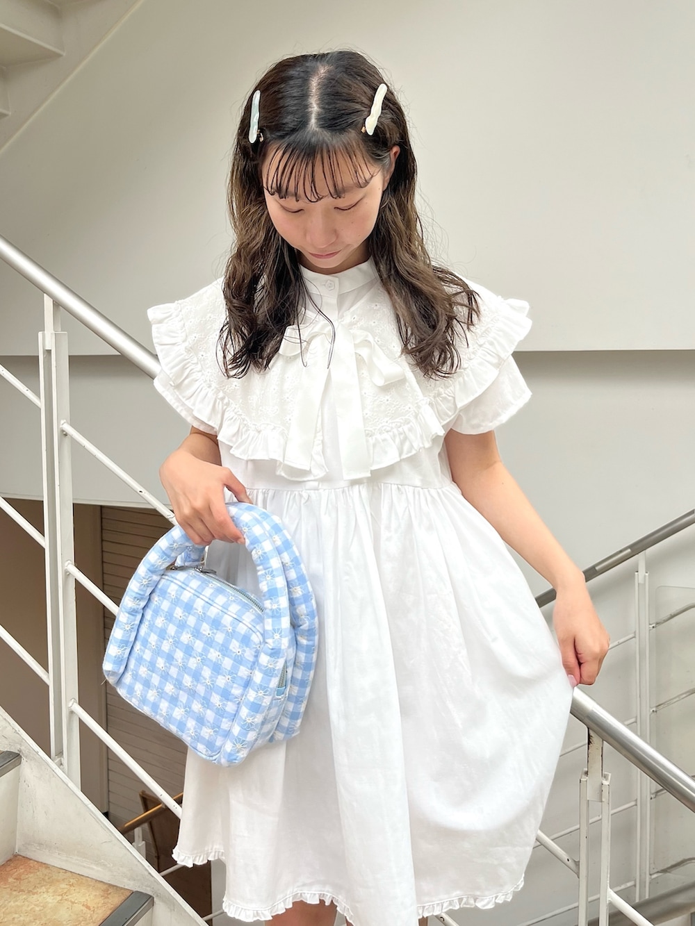 ホワイト系のワンピース、ブルー系のハンドバッグ、ピンク系のサンダルを着用したレディースの夏コーディネートの3枚目の写真