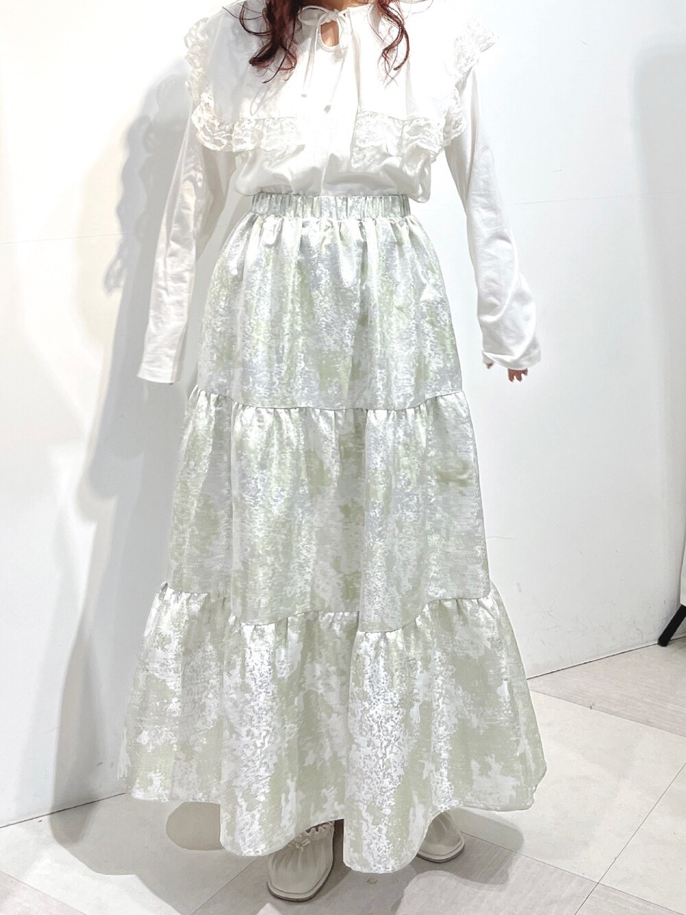 ホワイト系のTシャツ/カットソー、グリーン系のスカート、ホワイト系のパンプスを着用したレディースの冬コーディネートの5枚目の写真