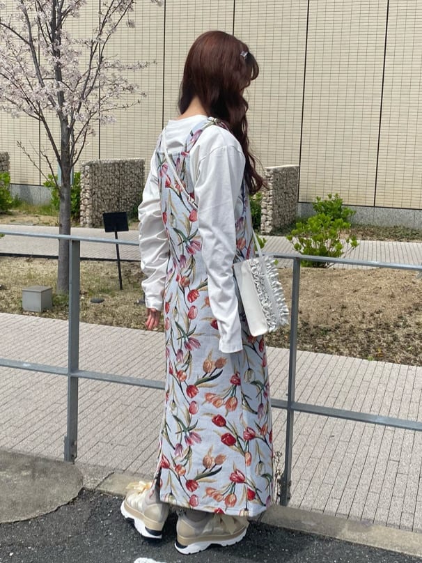 ブルー系のジャンパースカート、ホワイト系のスニーカー、ホワイト系のTシャツ/カットソーを着用したレディースの春コーディネートの2枚目の写真