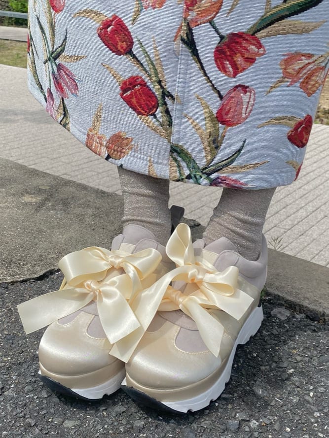 ブルー系のジャンパースカート、ホワイト系のスニーカー、ホワイト系のTシャツ/カットソーを着用したレディースの春コーディネートの6枚目の写真