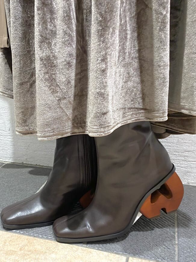 ブラウン系のスカート、ベージュ系のトレンチコート、ブラウン系のブーツを着用したレディースの秋コーディネートの6枚目の写真