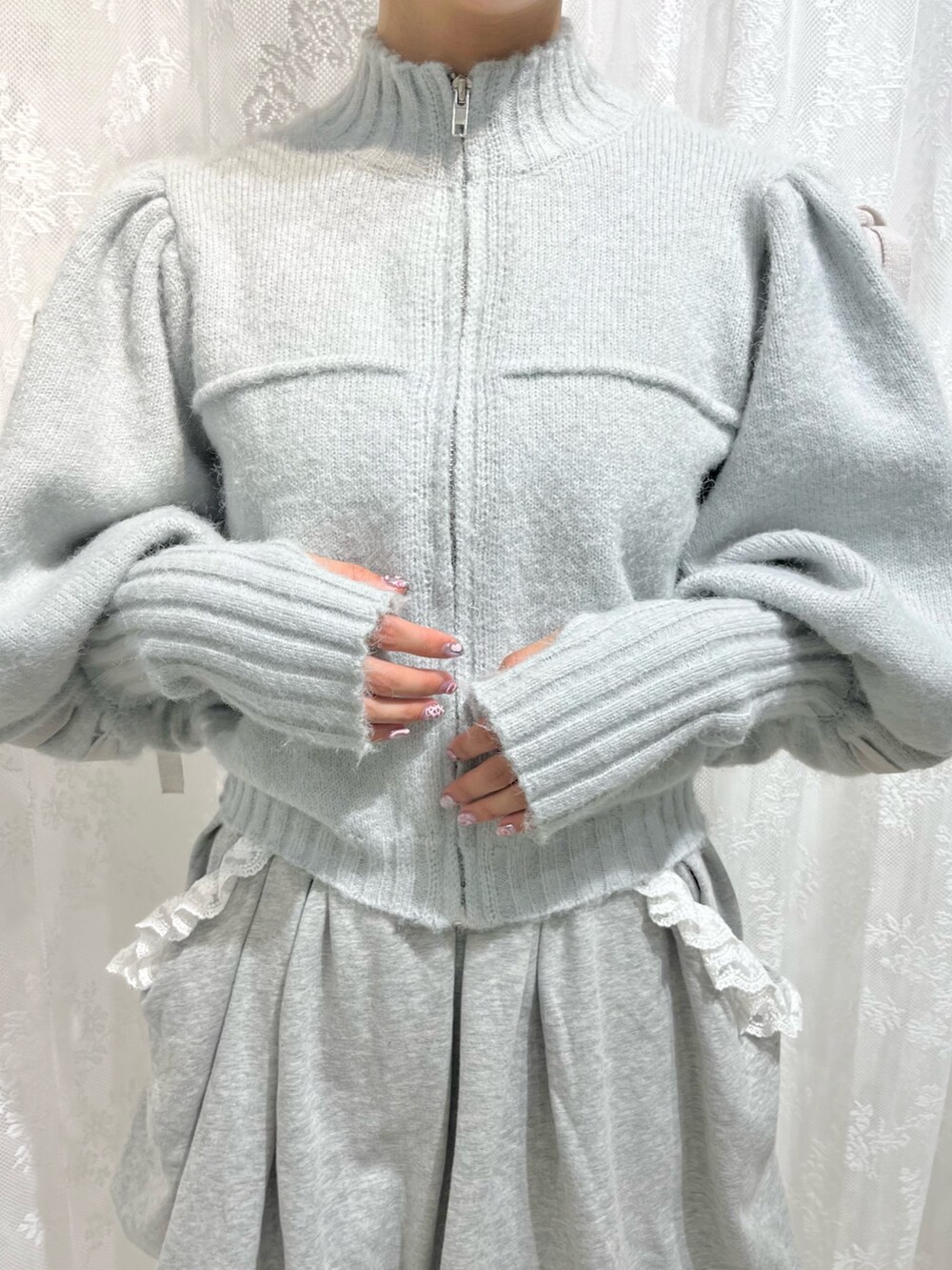 グリーン系のカーディガン/ボレロ、グレー系のスカート、ホワイト系のスニーカーを着用したレディースの秋コーディネートの4枚目の写真