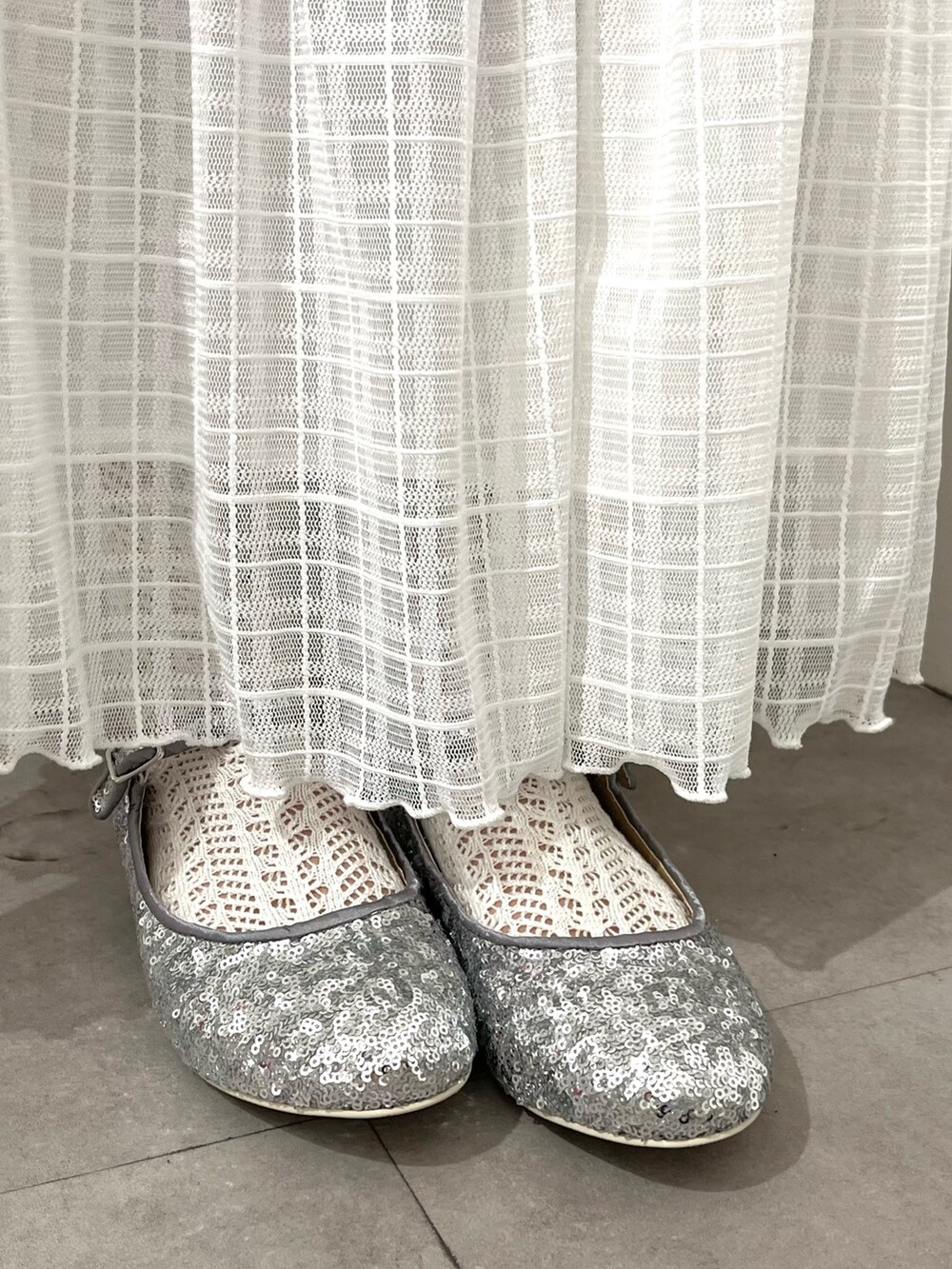 パープル系のニット/セーター、ホワイト系のスカート、シルバー系のパンプスを着用したレディースの春コーディネートの3枚目の写真