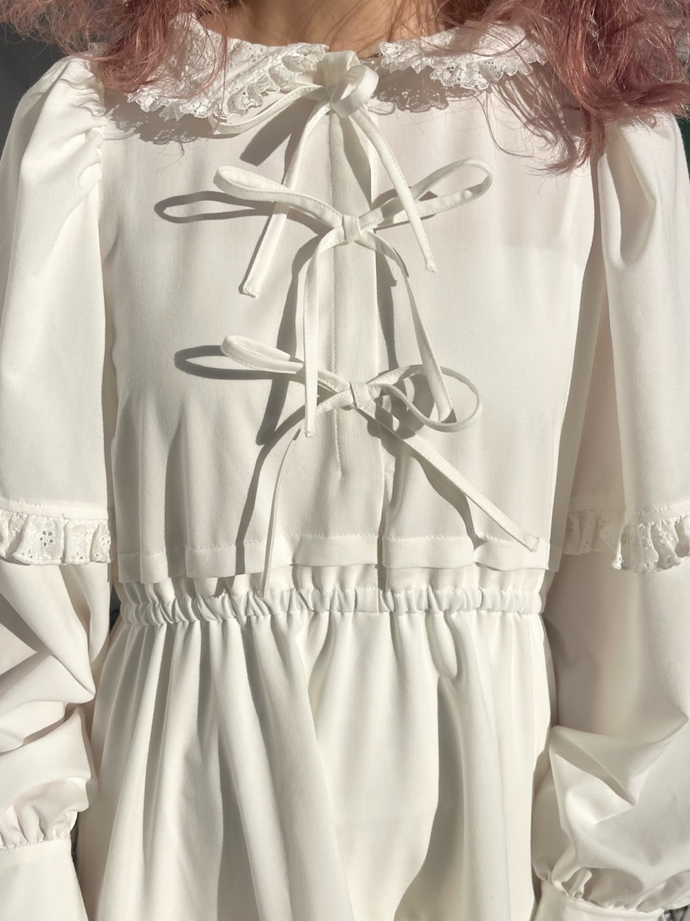 ホワイト系のワンピース、ピンク系のショルダーバッグ、ホワイト系のスニーカーを着用したレディースの冬コーディネートの7枚目の写真