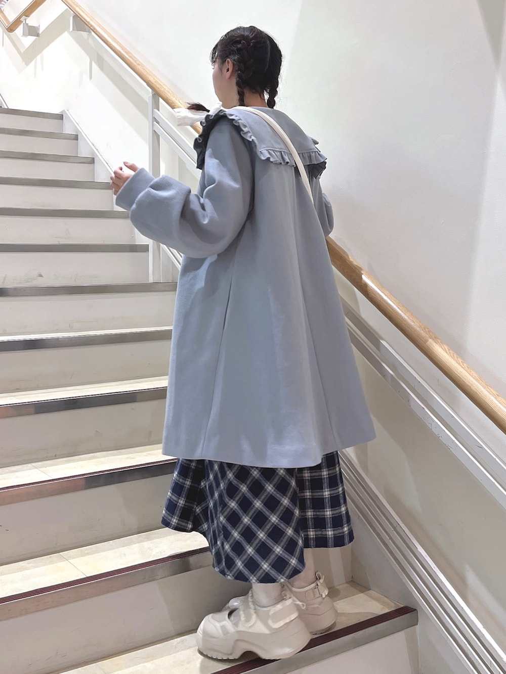 ブルー系のチェスターコート、ブルー系のワンピース、ホワイト系のショルダーバッグを着用したレディースの冬コーディネートの3枚目の写真