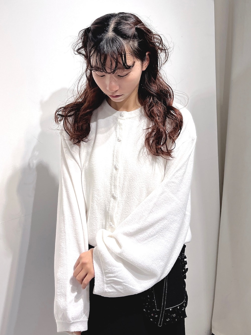 ホワイト系のカーディガン/ボレロ、ブラック系のデニムスカート、ブラック系のスニーカーを着用したレディースの冬コーディネートの6枚目の写真