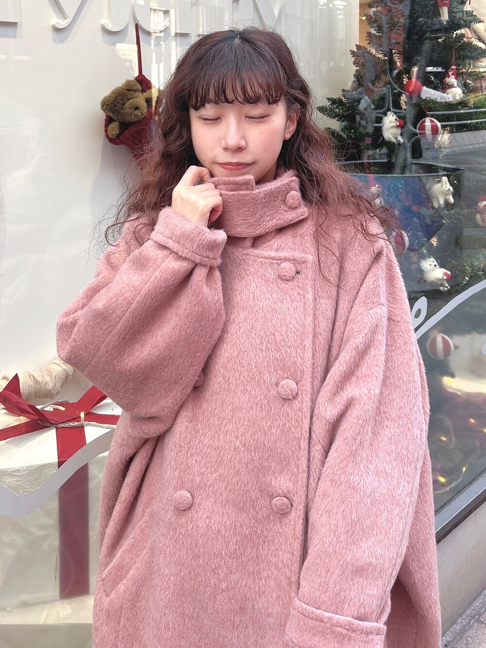 ピンク系のチェスターコート、ブラック系のカーディガン/ボレロ、ホワイト系のワンピースを着用したレディースの冬コーディネートの4枚目の写真