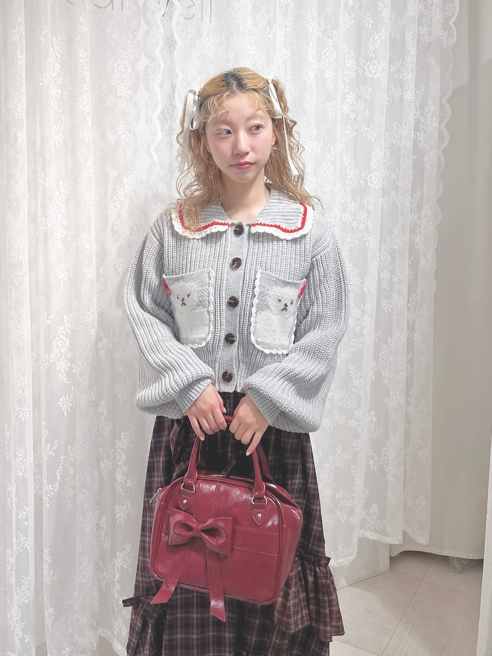 グレー系のカーディガン/ボレロ、レッド系のスカート、レッド系のハンドバッグを着用したレディースの夏コーディネートの6枚目の写真