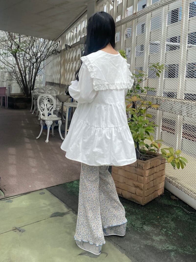 グレー系のサンダル、ホワイト系のチュニック、ブルー系のその他パンツを着用したレディースの秋コーディネートの4枚目の写真