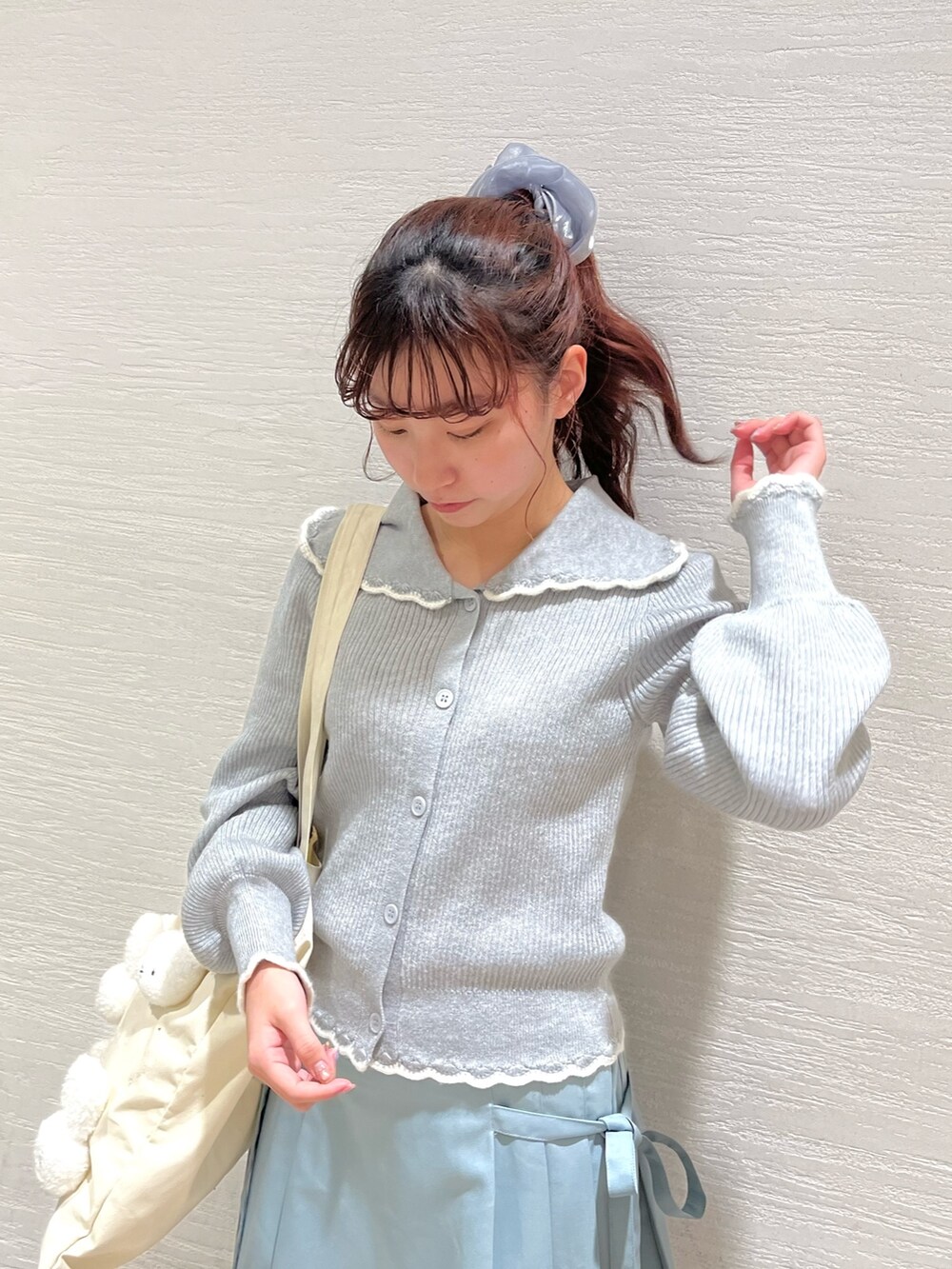 グレー系のニット/セーター、ブルー系のスカート、ホワイト系のトートバッグを着用したレディースの冬コーディネートの4枚目の写真