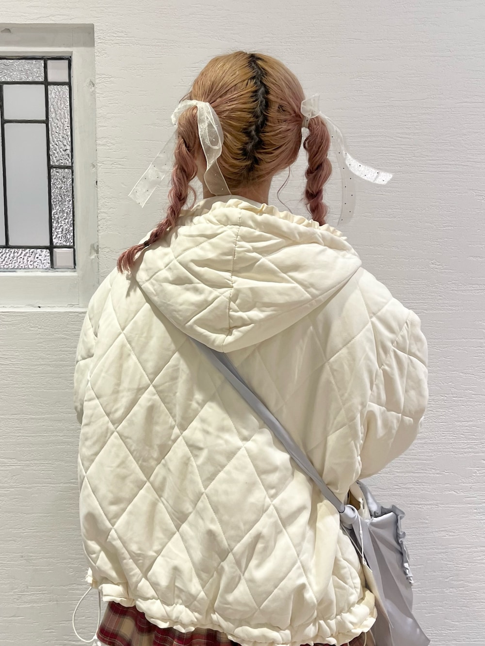 ホワイト系のダウンジャケット/コート、ホワイト系のニット/セーター、ブルー系のショルダーバッグを着用したレディースの冬コーディネートの6枚目の写真