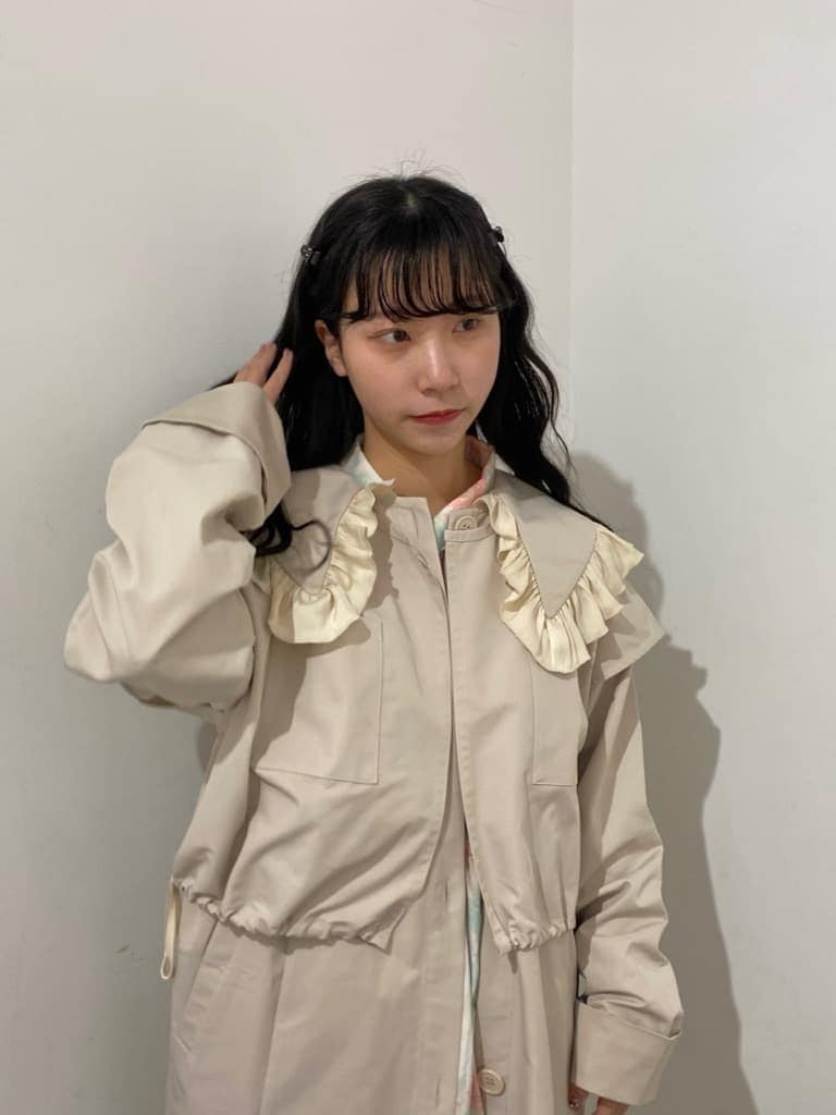 ホワイト系のトレンチコート、ピンク系のワンピース、ホワイト系のスニーカーを着用したレディースの冬コーディネートの4枚目の写真