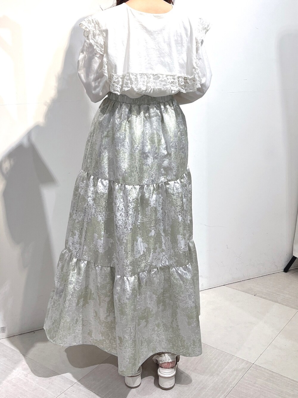 ホワイト系のTシャツ/カットソー、グリーン系のスカート、ホワイト系のパンプスを着用したレディースの冬コーディネートの6枚目の写真