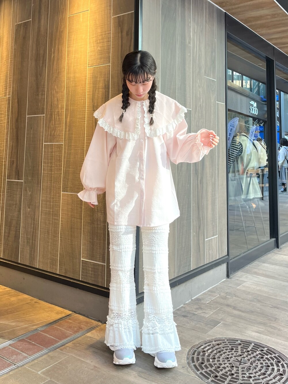 ピンク系のシャツ/ブラウス、ホワイト系のスラックス、ブルー系のスニーカーを着用したレディースの春コーディネートの2枚目の写真