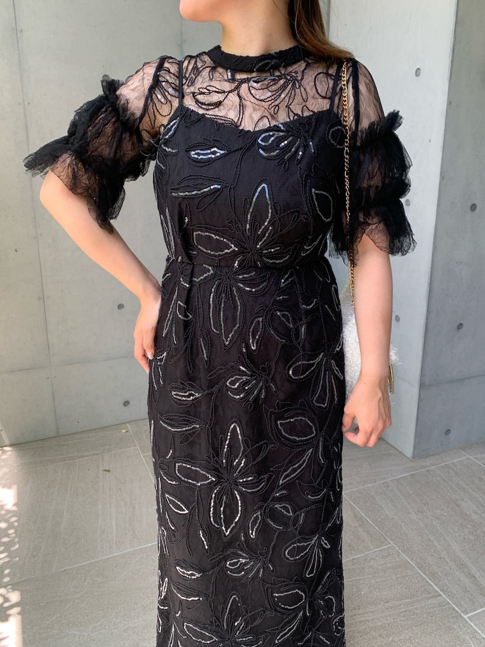 ブラック系のドレス、ベージュ系のパンプス、ホワイト系のバッグを着用したレディースの秋コーディネートの3枚目の写真