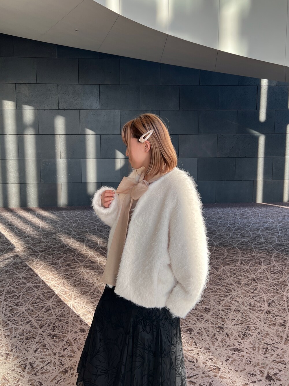 ブラック系のドレス、ホワイト系のノーカラージャケット、ベージュ系のシューズを着用したレディースの冬コーディネートの2枚目の写真