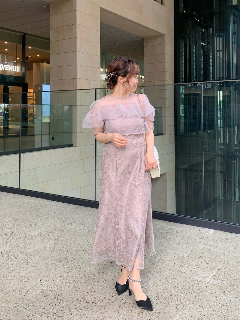 ベージュ系のドレス、ベージュ系のクラッチバッグ、ゴールド系のヘアピンを着用したレディースの春コーディネートの2枚目の写真