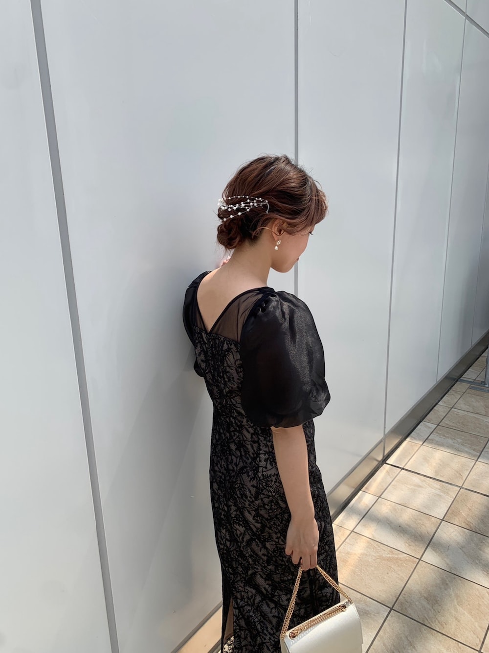 ブラック系のドレス、ブラック系のクラッチバッグ、ベージュ系のパンプスを着用したレディースの春コーディネートの6枚目の写真