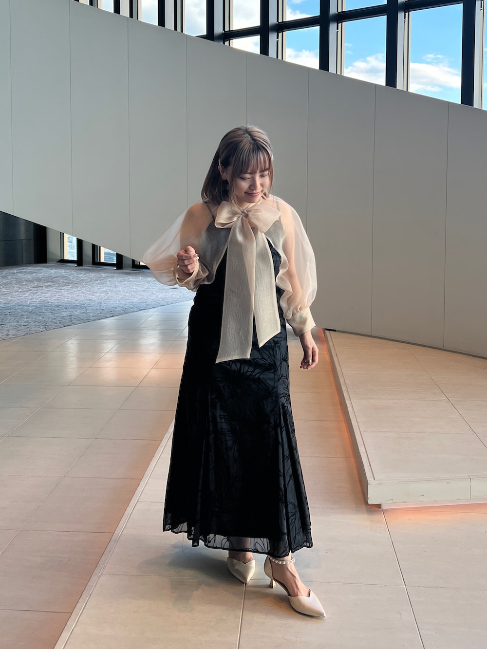 ブラック系のドレス、ホワイト系のノーカラージャケット、ベージュ系のシューズを着用したレディースの冬コーディネートの4枚目の写真