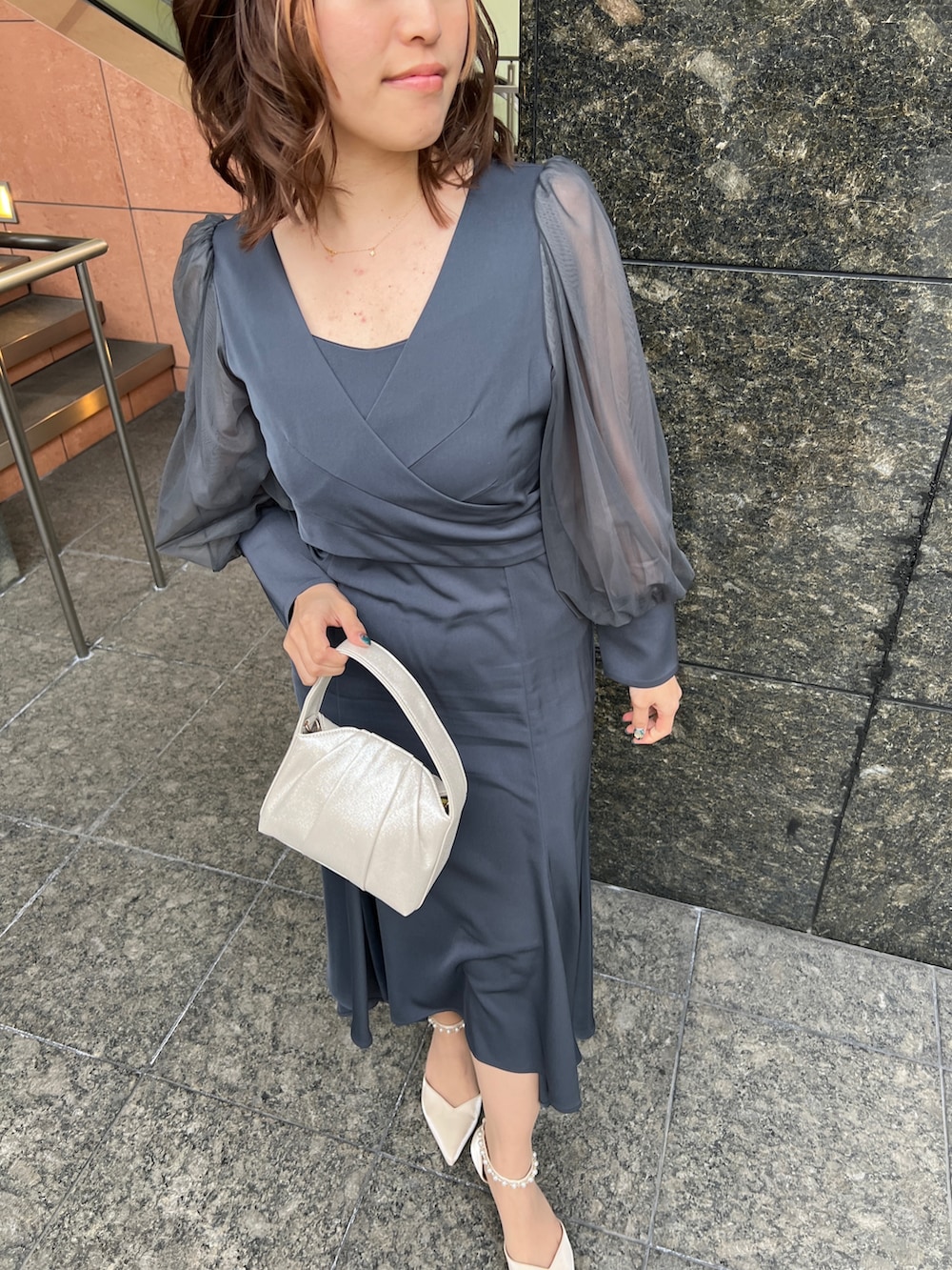 グリーン系のドレス、ベージュ系のハンドバッグ、ベージュ系のシューズを着用したレディースの春コーディネートの6枚目の写真