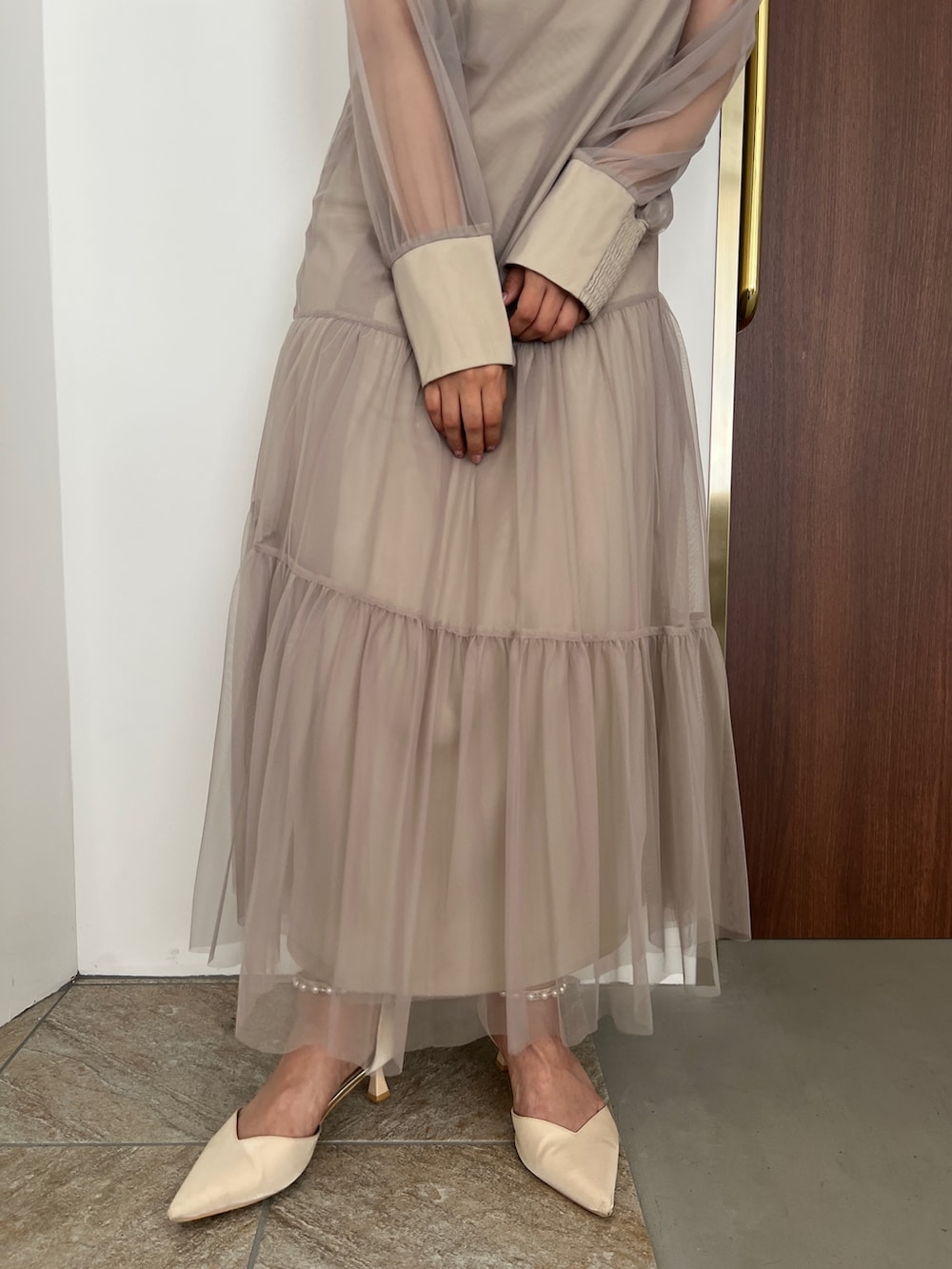 ベージュ系のドレス、ゴールド系のハンドバッグ、ベージュ系のシューズを着用したレディースの秋コーディネートの6枚目の写真