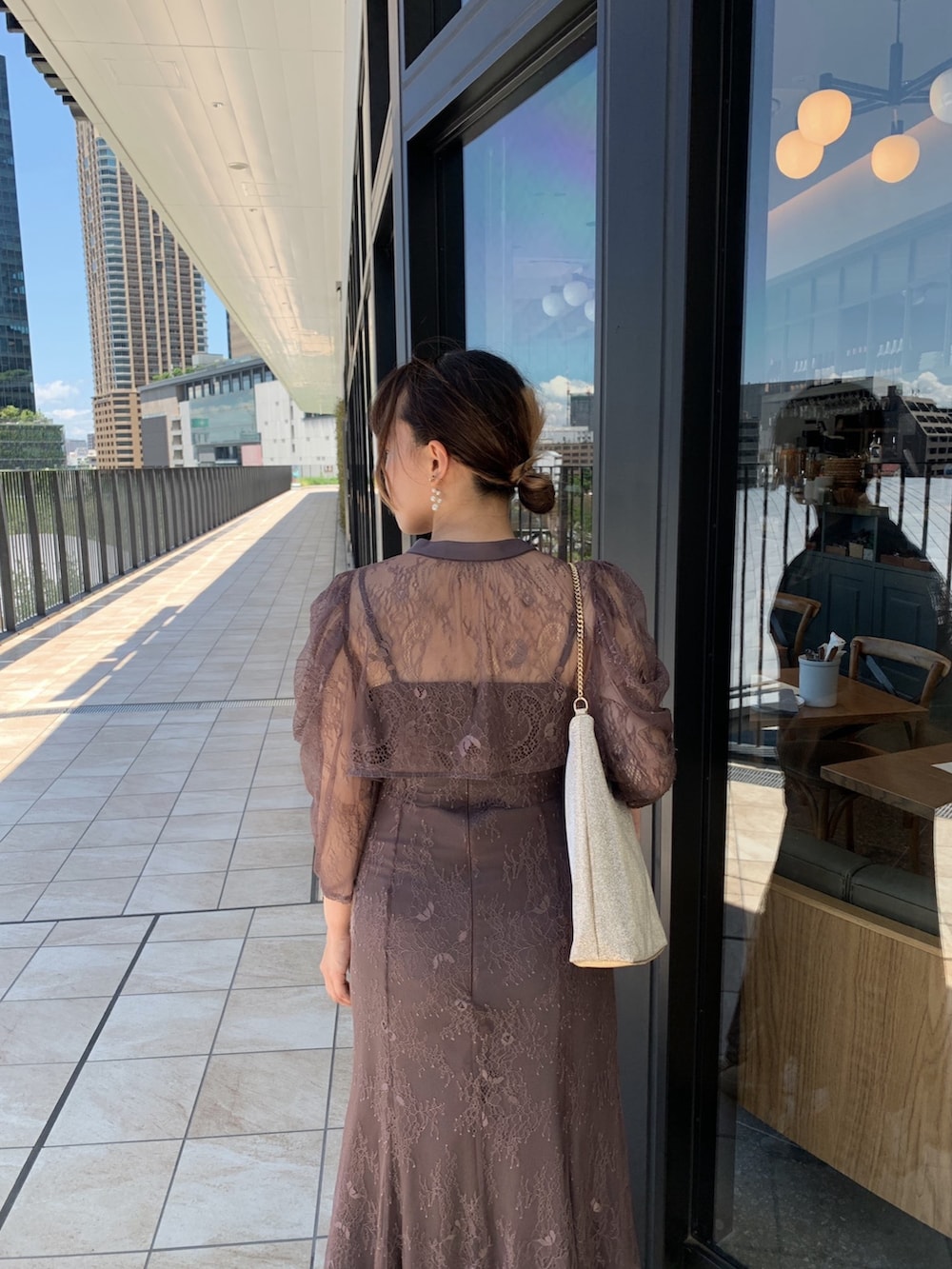 グレー系のドレス、ゴールド系のショルダーバッグ、ゴールド系のピアス（両耳用）を着用したレディースの夏コーディネートの5枚目の写真