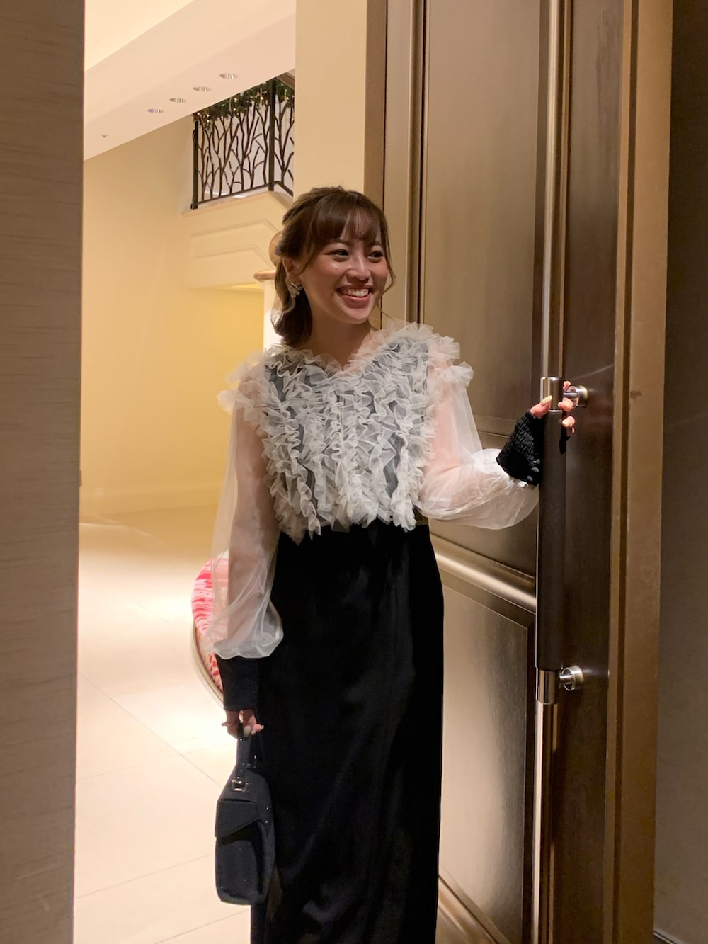 ブラック系のドレス、ブラック系のハンドバッグ、ゴールド系のヘアピンを着用したレディースの春コーディネートの5枚目の写真