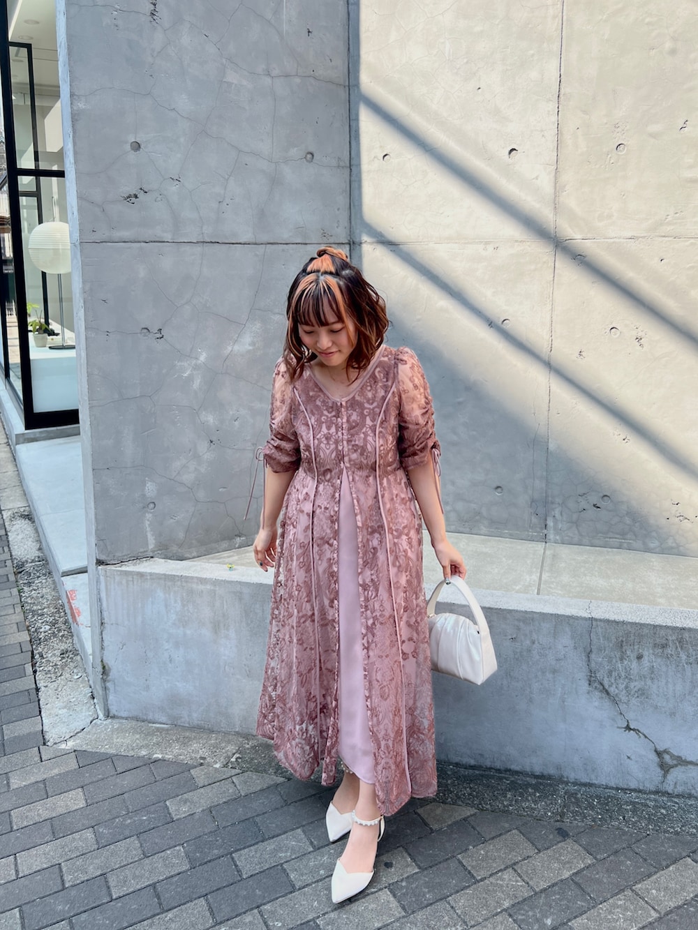 ピンク系のドレス、ベージュ系のハンドバッグ、ベージュ系のシューズを着用したレディースの春コーディネートの2枚目の写真