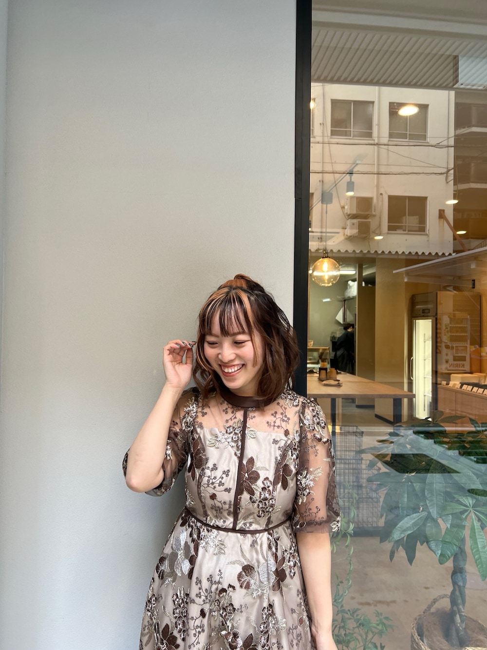 ブラウン系のドレス、ベージュ系のハンドバッグを着用したレディースの春コーディネートの3枚目の写真