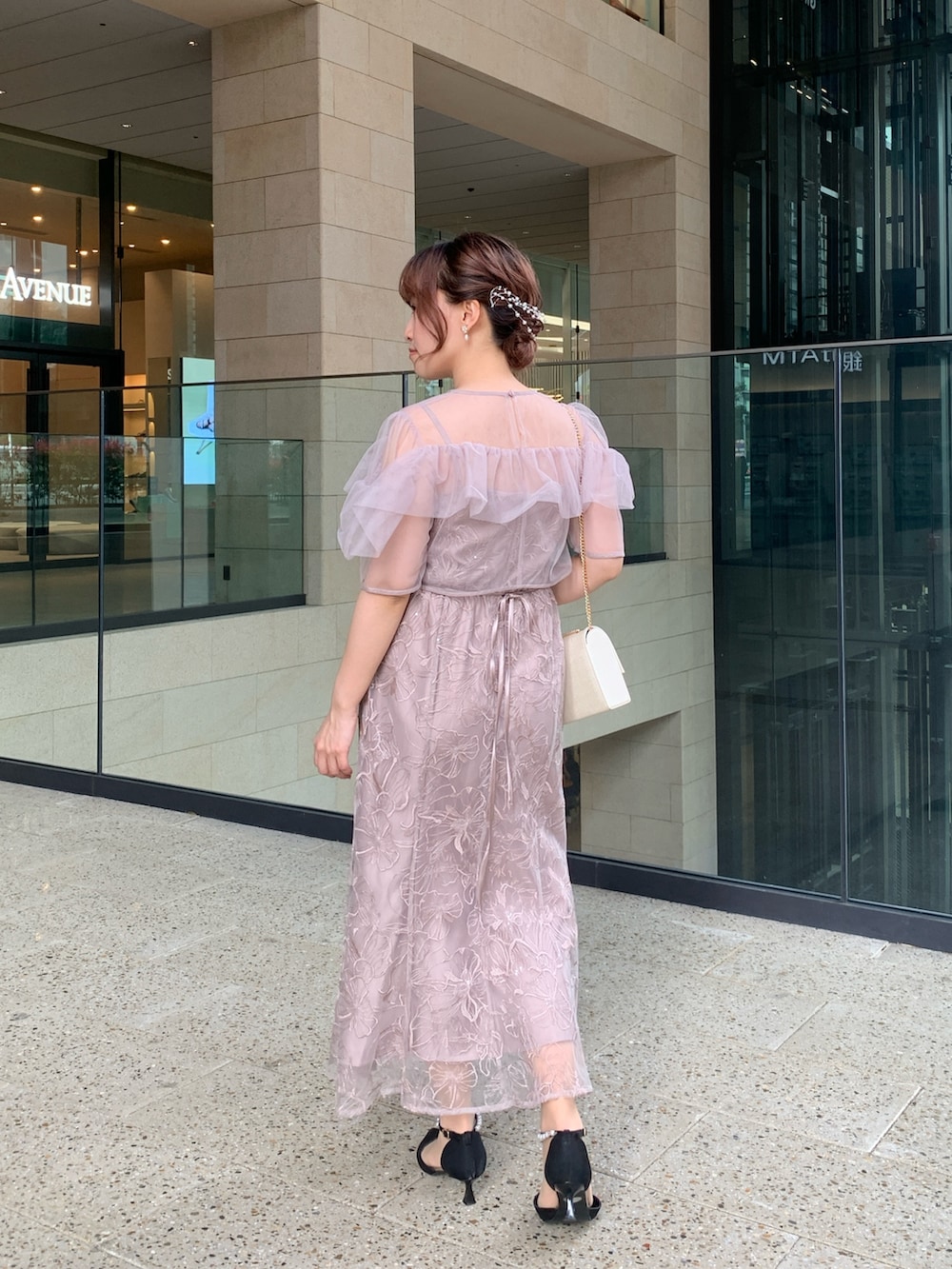 ベージュ系のドレス、ベージュ系のクラッチバッグ、ゴールド系のヘアピンを着用したレディースの春コーディネートの4枚目の写真