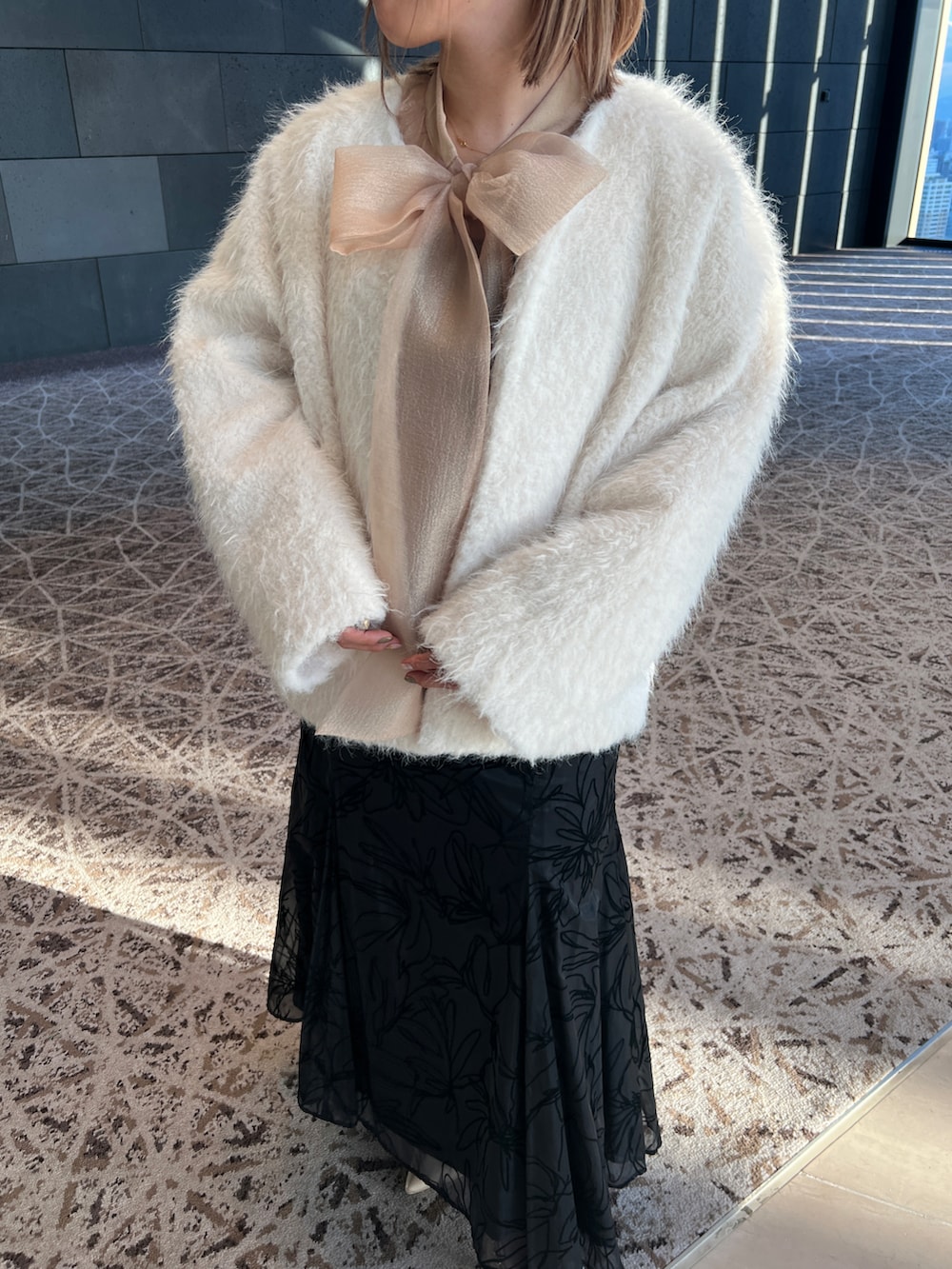 ブラック系のドレス、ホワイト系のノーカラージャケット、ベージュ系のシューズを着用したレディースの冬コーディネートの3枚目の写真