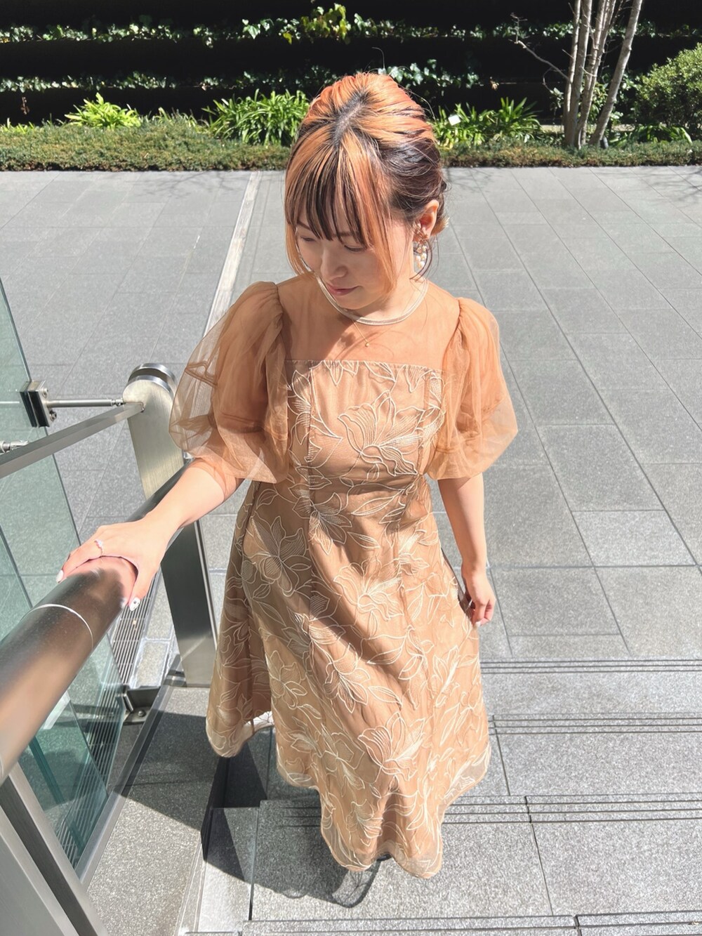 オレンジ系のドレス、ブラック系のパンプス、ブラック系のショルダーバッグを着用したレディースの春コーディネートの4枚目の写真