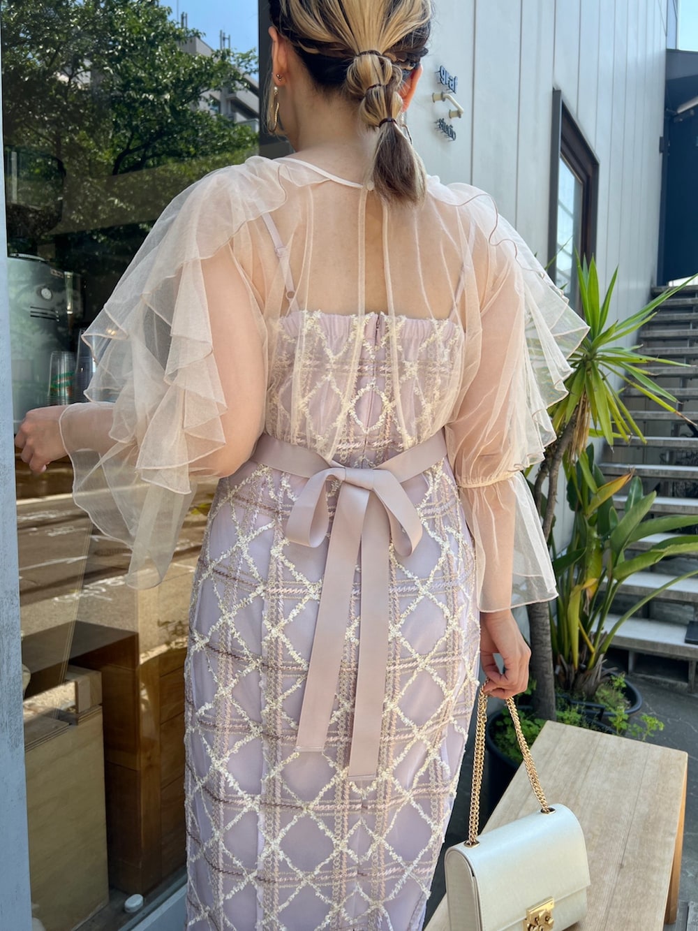 ベージュ系のクラッチバッグ、ベージュ系のパンプス、ピンク系のドレスを着用したレディースの夏コーディネートの3枚目の写真