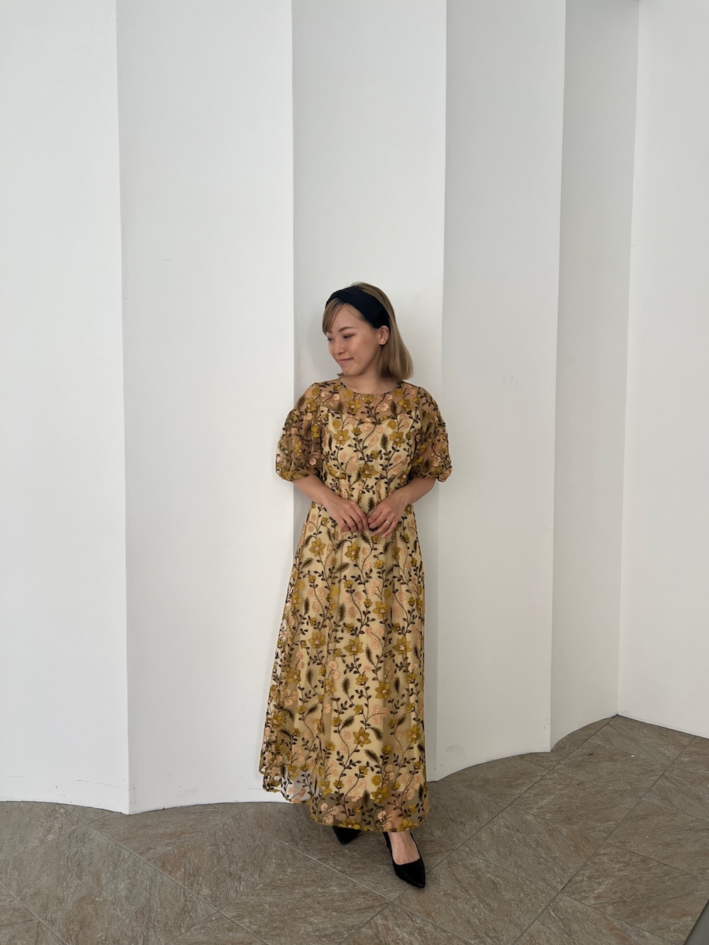 イエロー系のドレス、ブラック系のパンプス、ブラック系のカチューシャを着用したレディースの夏コーディネートの2枚目の写真