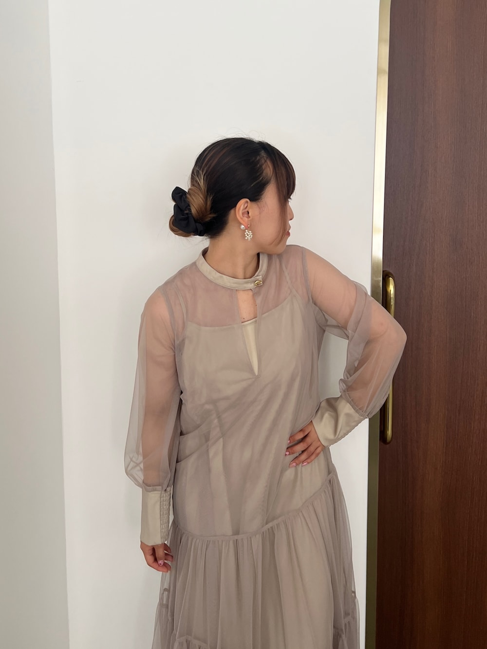 ベージュ系のドレス、ゴールド系のハンドバッグ、ベージュ系のシューズを着用したレディースの秋コーディネートの2枚目の写真