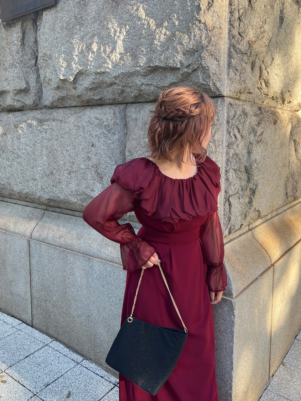 レッド系のドレス、ブラック系のショルダーバッグ、ブラック系のパンプスを着用したレディースの秋コーディネートの4枚目の写真