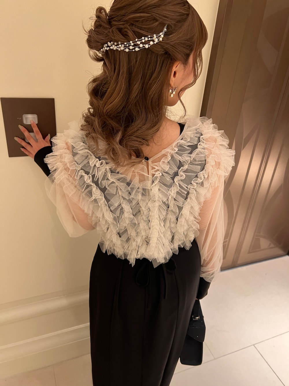 ブラック系のドレス、ブラック系のハンドバッグ、ゴールド系のヘアピンを着用したレディースの春コーディネートの3枚目の写真