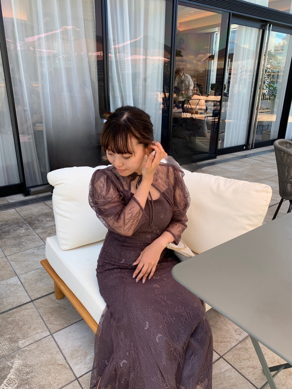 グレー系のドレス、ゴールド系のショルダーバッグ、ゴールド系のピアス（両耳用）を着用したレディースの夏コーディネートの4枚目の写真