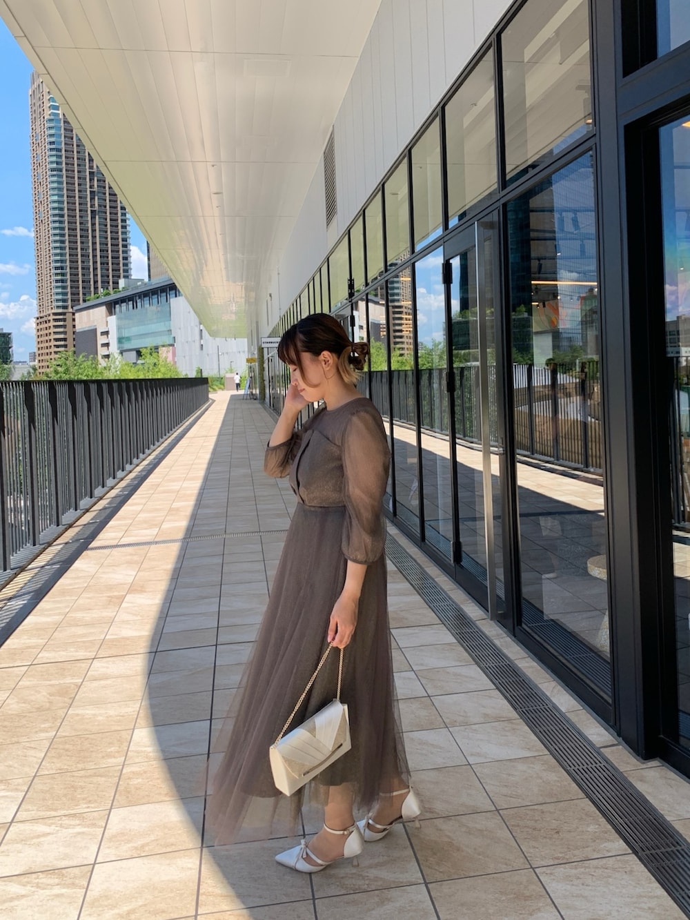 グリーン系のドレス、ベージュ系のクラッチバッグ、ベージュ系のパンプスを着用したレディースの夏コーディネートの3枚目の写真